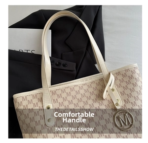 Detail of monogram M print tote bag with leather straps and metallic charm pendant