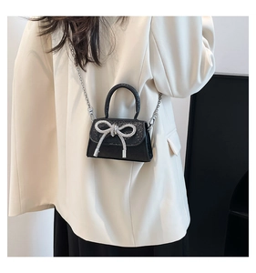 Gros plan sur un mini sac noir scintillant avec un détail de nœud en strass argenté