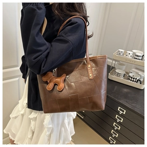 Detailed texture of brown patchwork tote bag with cute dog charm on casual shoulder strap