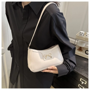 Detailed close-up of a white underarm bag with a gold metal bow buckle and PU leather