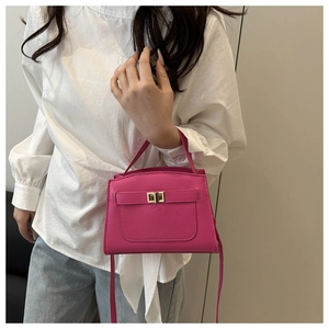 Detail of fuchsia lychee-grain mini handbag with golden clasp shown with model