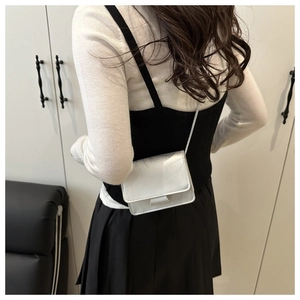 Rear view of a model wearing the silver mini flap crossbody bag with metallic finish