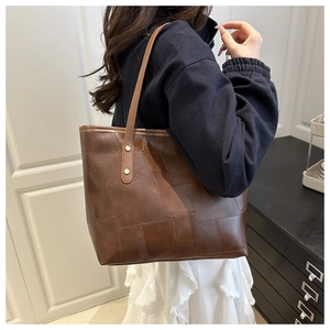 Brown tote bag with vintage stitching and gold rivets shown on a model's shoulder