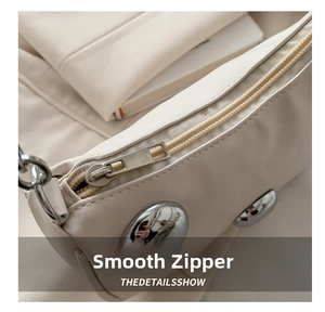 Macro shot of smooth zipper and silver rivet details on cream large capacity tote bag
