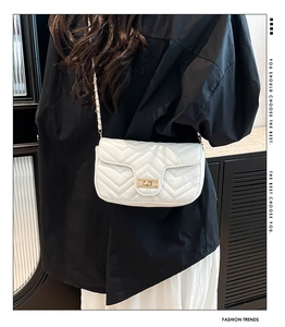 Gros plan du sac bandoulière blanc matelassé avec motif en V et fermoir rotatif doré