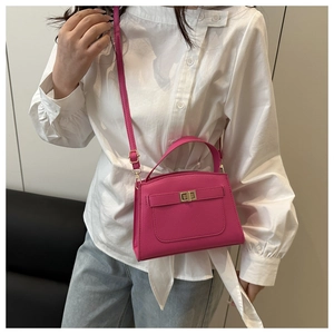Detail view of fuchsia leather crossbody bag with gold-tone hardware and pebble texture