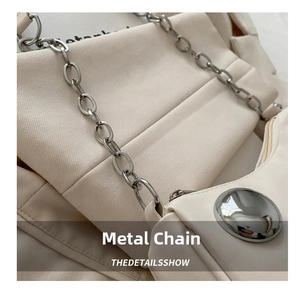 Detail of silver chain strap and metal buckle on beige matte leather handbag