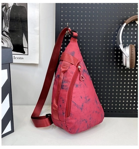 Detail of red tie-dye nylon sling bag hanging on a stylish urban mesh wall setup