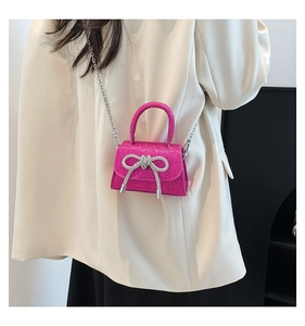 Macro detail of fuchsia glitter mini bag with a sparkling silver rhinestone bow accent