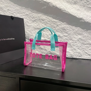 Transparent PVC tote bag with pink trim, blue handles and bold TOTE BAG print