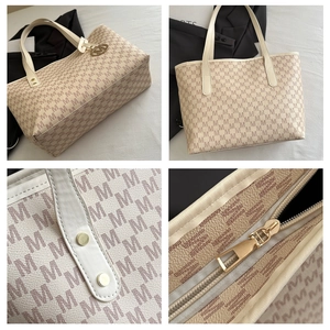 Close-up of beige tote bag showing monogram pattern, lychee texture, and gold-tone hardware