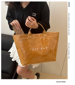 Detail of a brown waterproof paper tote bag featuring bold white TOTE BAG text print