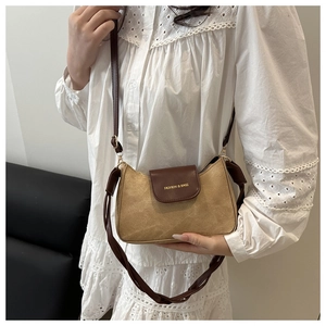 Détail d'un petit sac bandoulière marron bicolore avec boucle dorée sur un haut en dentelle
