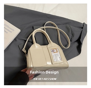 Détail du sac Boston en cuir verni blanc cassé avec une fente transparente pour carte