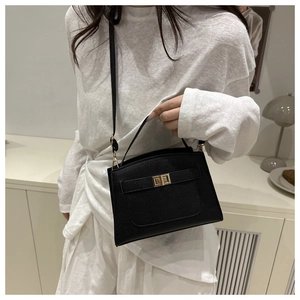 Close-up of black lychee grain leather handbag with gold twist lock and fine texture