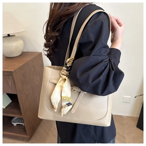 Detail of khaki tote bag with silk scarf on handle and sleek faux leather finish