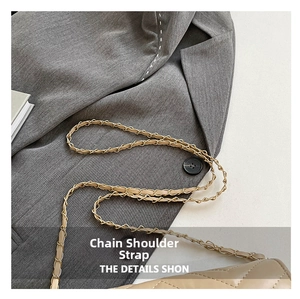 Détail de la bandoulière en chaîne de métal doré et cuir beige sur un sac matelassé