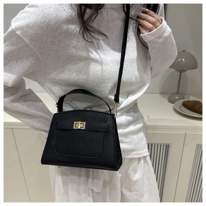 Close-up of black lychee grain leather handbag featuring gold rotating metal lock buckle