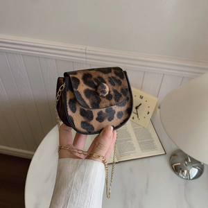 Mini-Satteltasche mit Leopardenmuster und goldener Kette in stilvollem Wohnambiente