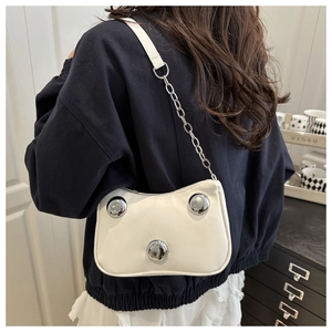 Detail of white studded hobo bag with silver metallic chain strap on shoulder