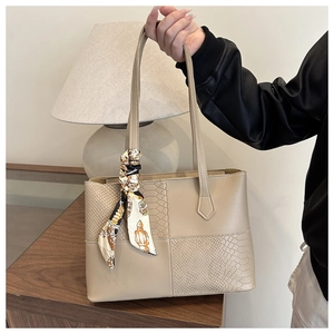 Detail of beige tote bag featuring textured faux snake skin panels and silk scarf handle