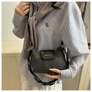 Détail d'un sac hobo gris foncé avec rabat en cuir noir et bandoulière tressée