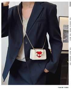 Détail du mini sac bandoulière en cuir blanc avec cœur rouge et décorations de perles