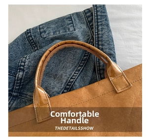 Macro detail of brown tote bag handle with reinforced stitching and textured paper finish