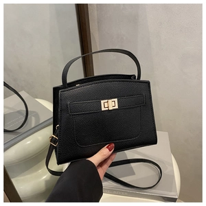 Detail of black lychee grain leather handbag with gold rotating lock and top handle