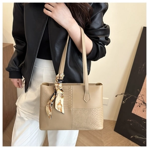 Detail of beige faux snake skin patchwork tote bag featuring a decorative silk scarf handle