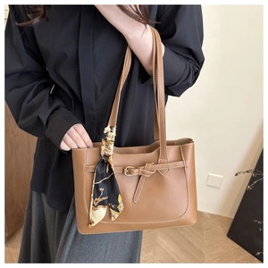 Close-up of brown tote bag with white stitching detail and decorative printed silk scarf