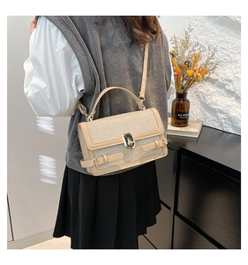 Close-up of a glittering beige crossbody bag with metallic lock shown on a model