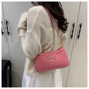 Close-up of pink crescent underarm bag featuring a golden bow metal accessory detail