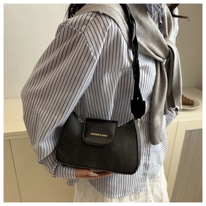 Vue détaillée du sac besace noir rétro avec logo doré et texture en cuir mélangé