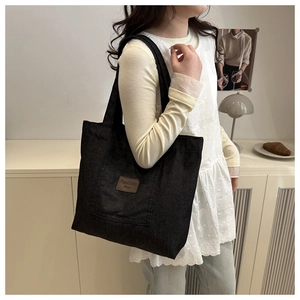 Detail of black canvas tote bag showing the vintage leather patch with fashion lettering