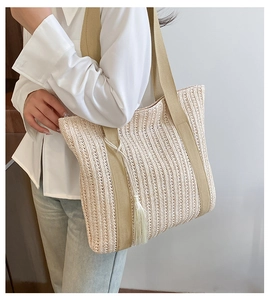 Dettaglio della borsa tote in paglia intrecciata beige con nappe e ampi spallacci in tessuto