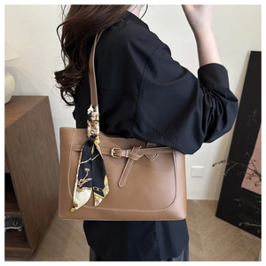 Brown leather tote with contrast stitching and decorative scarf shown on shoulder