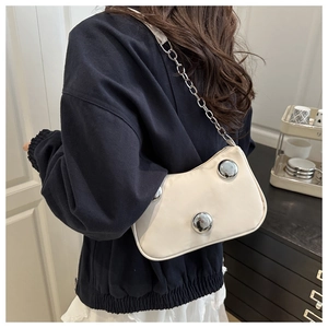 Detail of cream shoulder bag with silver metallic spheres and chunky chain strap