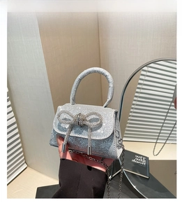 Detail of silver sequined mini bag featuring a rhinestone bow and chain strap