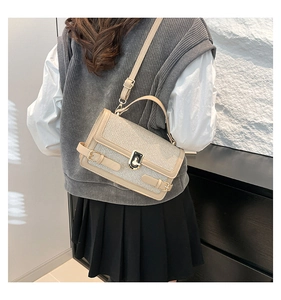 Close-up of beige woven crossbody bag featuring a golden twist lock and adjustable strap