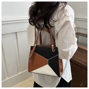 Detail of geometric patchwork leather handbag with woven texture and gold eyelets