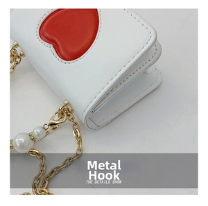Détail du mini sac en cuir blanc avec patch coeur rouge et chaîne en perles dorées