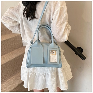 Détail du sac Boston bleu clair avec fente pour carte porté par un mannequin en intérieur