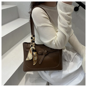 Brown leather tote bag featuring a decorative patterned silk scarf and metal buckle detail