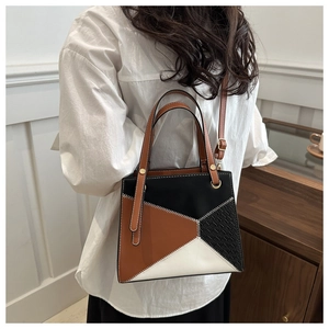 Detail of color-block tote bag with woven texture, golden ring handle and contrast stitching
