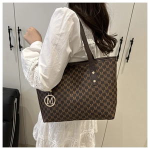 Detail of dark brown tote bag with M letter jacquard pattern and metal charm
