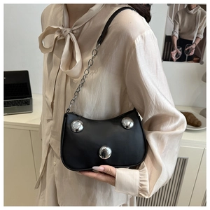 Detail of black crescent shoulder bag featuring three silver spherical metallic studs