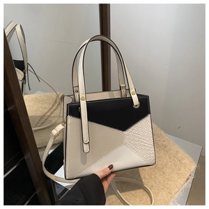 Detail of color-block tote bag with crocodile texture and elegant gold hardware accents