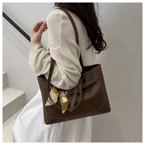 Detail of coffee brown leather tote bag with contrast stitching and decorative silk scarf