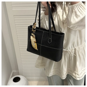 Detail of black tote bag with silk scarf accessory and contrast white stitching